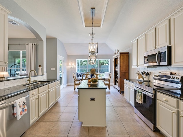 kitchen with stainless steel appliances, lofted ceiling, a kitchen island, and plenty of natural light