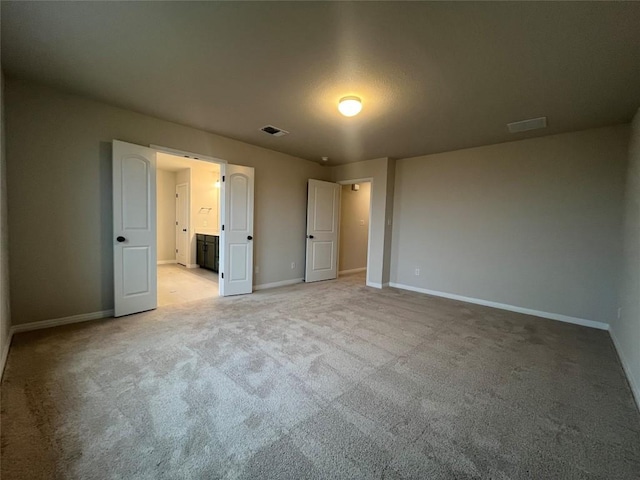 unfurnished bedroom with light carpet and ensuite bathroom