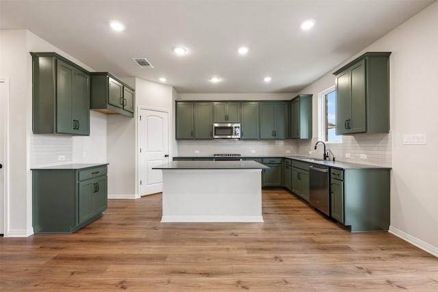 kitchen featuring stainless steel appliances, sink, green cabinets, and light hardwood / wood-style flooring