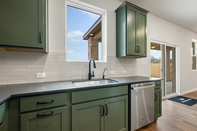 kitchen with sink, green cabinetry, light hardwood / wood-style flooring, dishwasher, and decorative backsplash