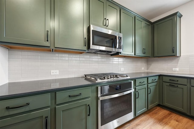 kitchen with tasteful backsplash, light hardwood / wood-style flooring, green cabinetry, and appliances with stainless steel finishes