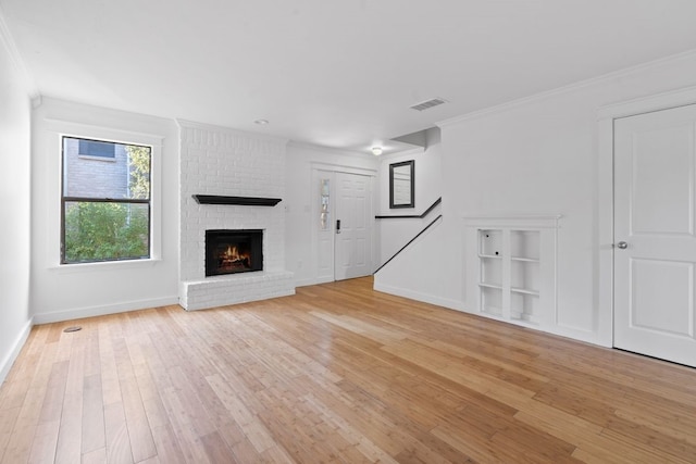 unfurnished living room featuring a brick fireplace, light hardwood / wood-style flooring, and ornamental molding