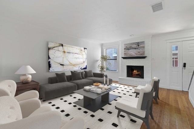 living room featuring a brick fireplace and light hardwood / wood-style floors