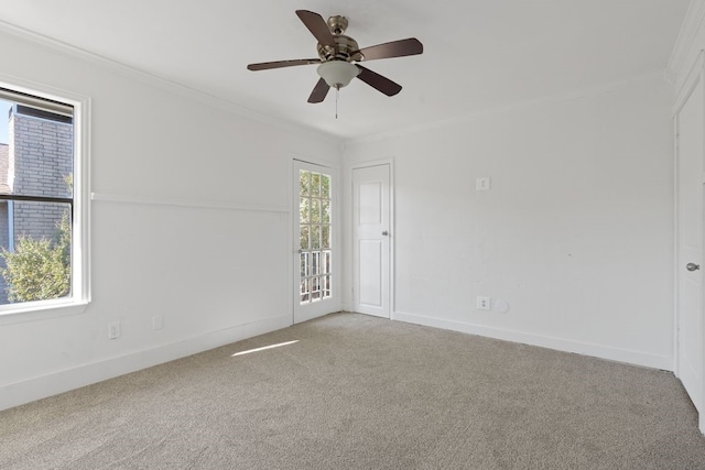 carpeted spare room featuring a wealth of natural light, ceiling fan, and crown molding