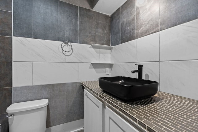 bathroom with toilet, vanity, and tile walls