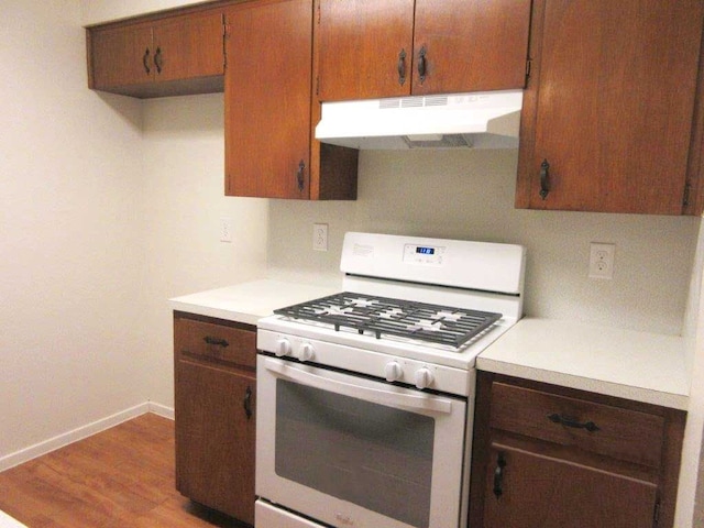 kitchen with white range with gas stovetop and hardwood / wood-style floors