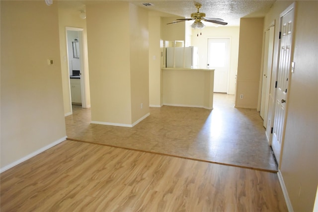 empty room featuring ceiling fan, a textured ceiling, and light wood-type flooring