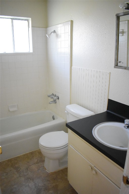 full bathroom with vanity, tiled shower / bath combo, and toilet