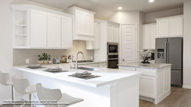 kitchen with appliances with stainless steel finishes, a center island with sink, and white cabinets