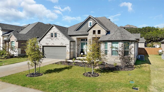 view of front of house featuring a garage, central air condition unit, and a front lawn