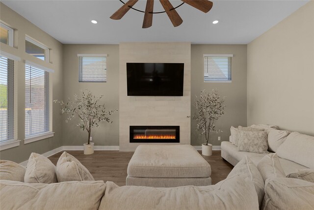 living room with a large fireplace, ceiling fan, hardwood / wood-style floors, and plenty of natural light