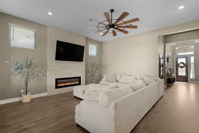 living room featuring ceiling fan, dark hardwood / wood-style floors, and a tile fireplace