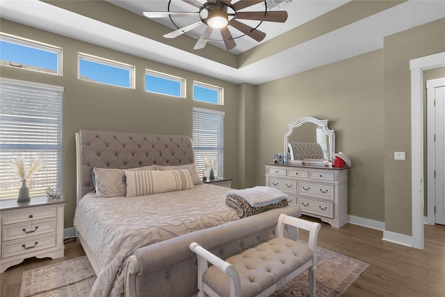 bedroom featuring light hardwood / wood-style flooring, ceiling fan, and a raised ceiling