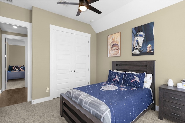 carpeted bedroom with ceiling fan, a closet, and vaulted ceiling