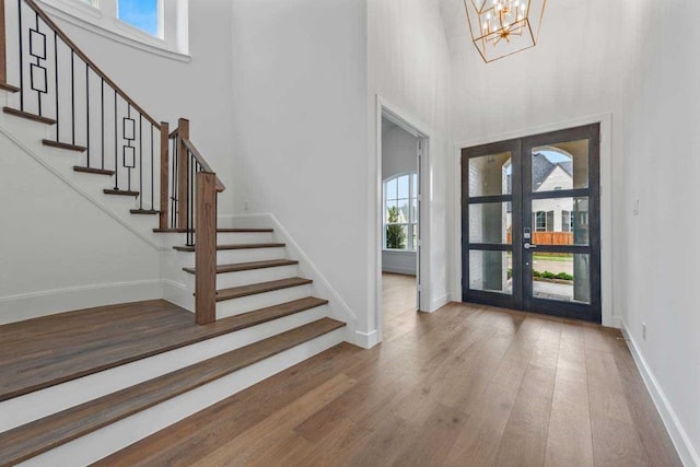 foyer entrance featuring an inviting chandelier, a wealth of natural light, french doors, and wood-type flooring