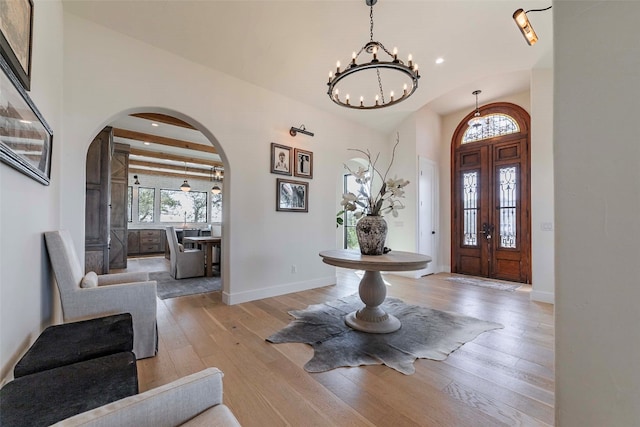 entryway featuring a chandelier, light hardwood / wood-style floors, beam ceiling, and french doors