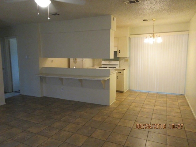 kitchen with kitchen peninsula, hanging light fixtures, a breakfast bar, and white cabinets