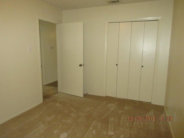 unfurnished bedroom with a closet and light colored carpet