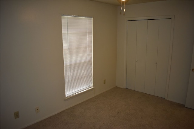 unfurnished bedroom featuring light carpet and a closet