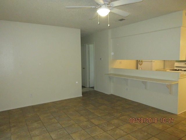 interior space with ceiling fan and a breakfast bar area