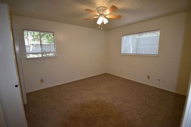 empty room with a textured ceiling, ceiling fan, and dark carpet