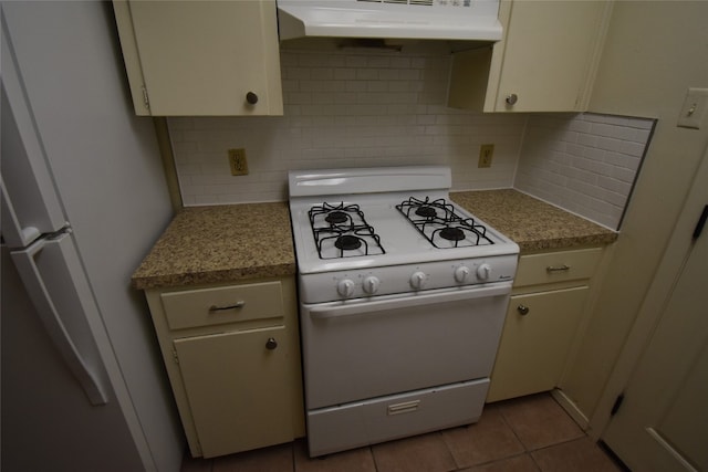 kitchen with backsplash, white appliances, light tile patterned floors, and cream cabinetry