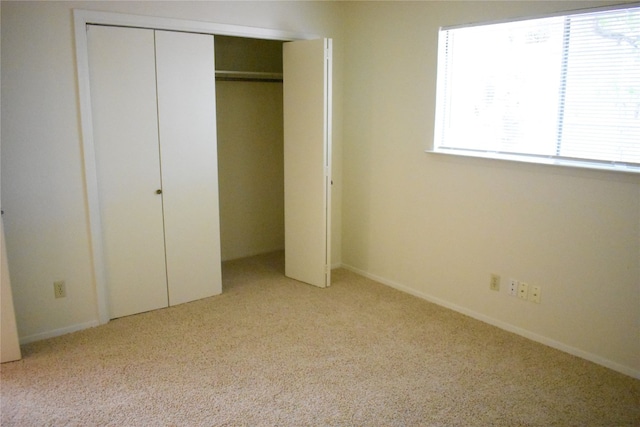 unfurnished bedroom featuring a closet, multiple windows, and light carpet