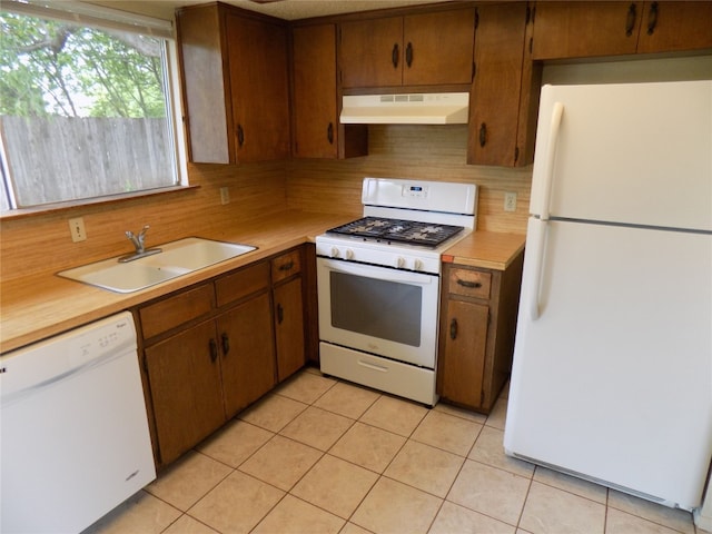 kitchen with tasteful backsplash, white appliances, sink, and light tile patterned floors