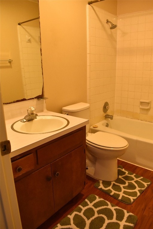 full bathroom featuring toilet, vanity, tiled shower / bath, and wood-type flooring