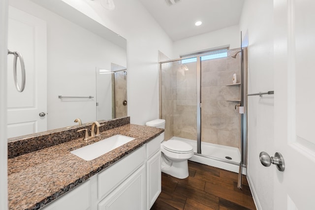 bathroom with toilet, vanity, hardwood / wood-style flooring, and a shower with shower door