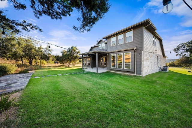 back of house with central air condition unit, a lawn, and a patio area