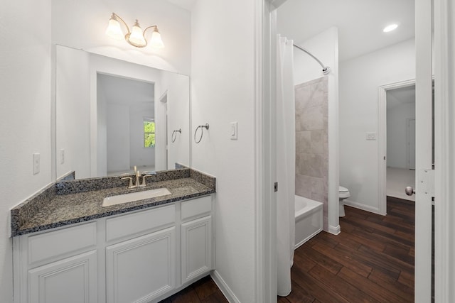 full bathroom featuring toilet, wood-type flooring, vanity, and  shower combination