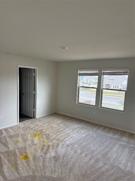 unfurnished room featuring a textured ceiling and light carpet