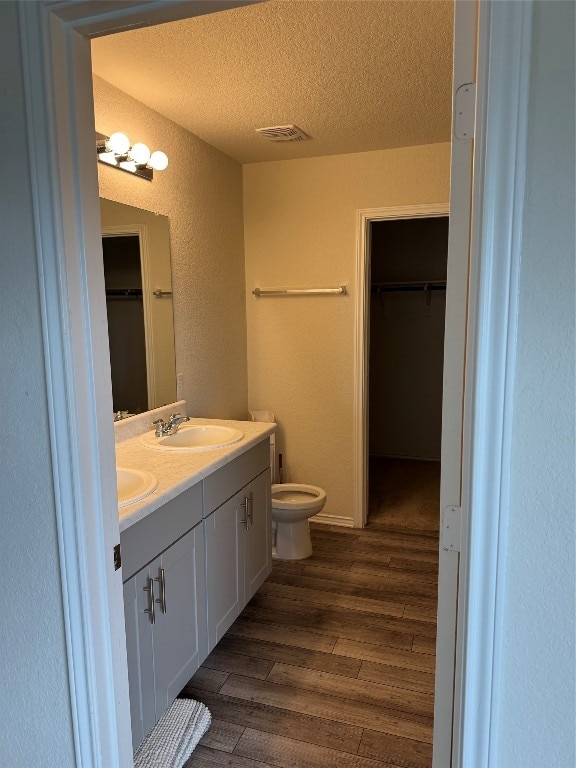 bathroom with wood-type flooring, a textured ceiling, toilet, and vanity