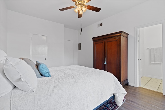 bedroom with hardwood / wood-style flooring, ceiling fan, and ensuite bath