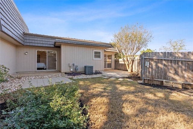 rear view of house with central AC unit, a lawn, and a patio