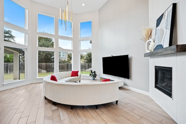 living room featuring a chandelier, a high ceiling, a large fireplace, and a healthy amount of sunlight