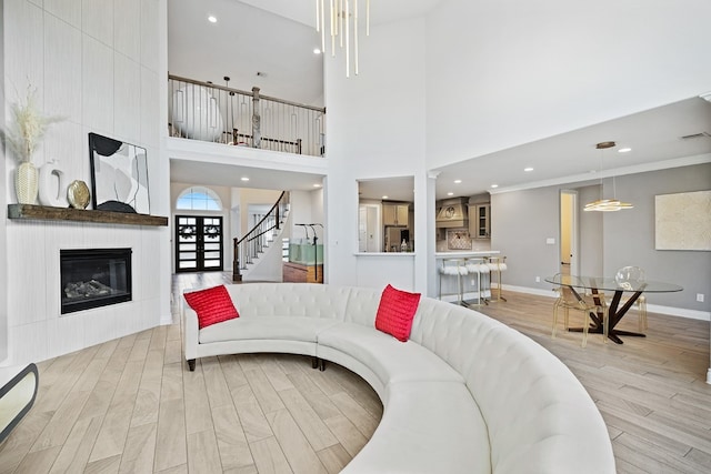 living room featuring a towering ceiling, a large fireplace, and crown molding