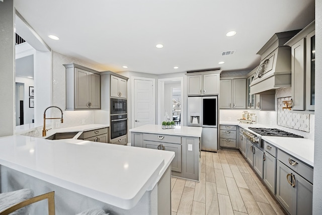 kitchen with a breakfast bar area, gray cabinetry, and black appliances