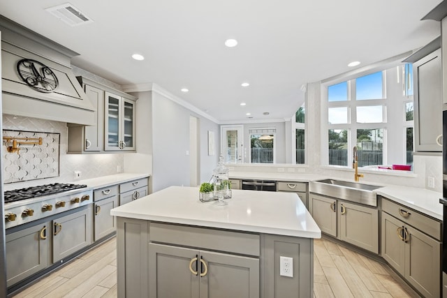 kitchen featuring gray cabinetry, sink, a center island, gas stovetop, and tasteful backsplash