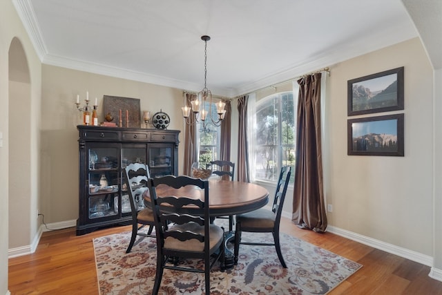 dining area featuring an inviting chandelier, ornamental molding, and hardwood / wood-style flooring