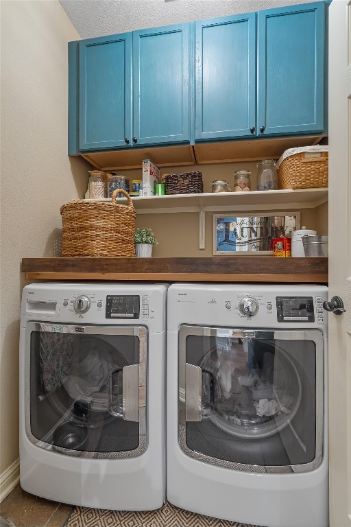 laundry room featuring washer and dryer, a textured ceiling, cabinets, and tile patterned flooring