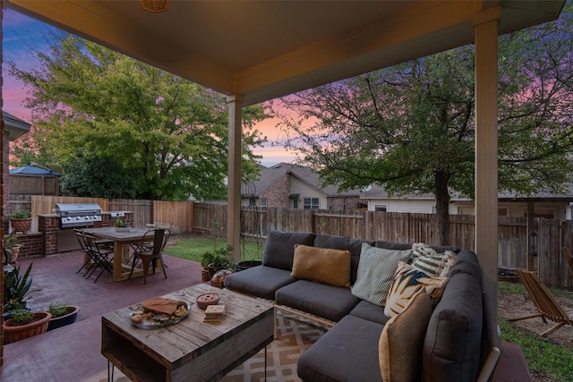 patio terrace at dusk featuring an outdoor living space, a grill, and exterior kitchen