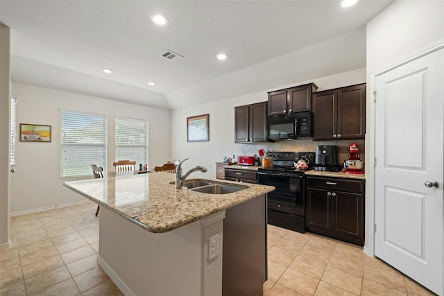 kitchen with sink, black appliances, light stone counters, tasteful backsplash, and a kitchen island with sink