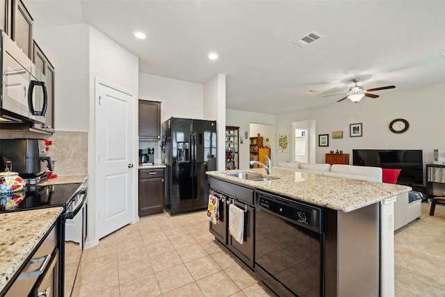 kitchen with sink, black appliances, light stone counters, dark brown cabinets, and a kitchen island with sink