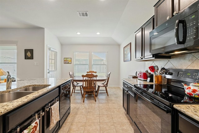 kitchen featuring light stone counters, vaulted ceiling, black appliances, sink, and dark brown cabinets