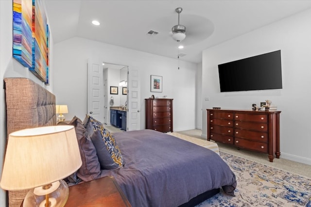 bedroom with ceiling fan, ensuite bathroom, light carpet, and vaulted ceiling