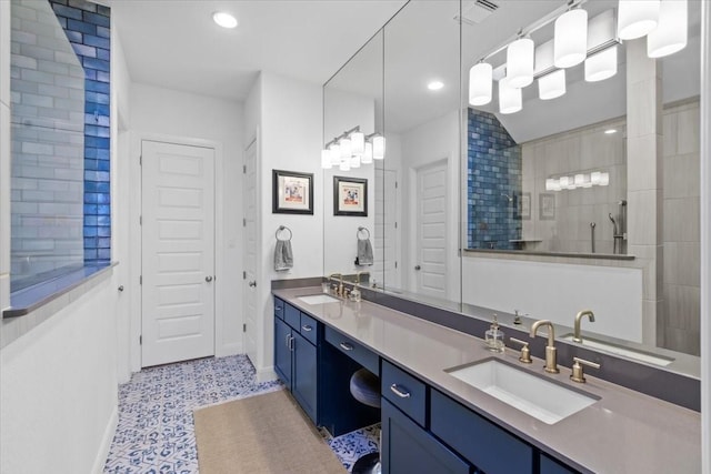 bathroom featuring tile patterned flooring, a tile shower, and vanity