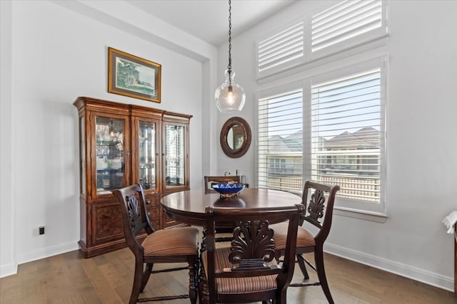 dining room with dark wood-type flooring, a healthy amount of sunlight, and a towering ceiling