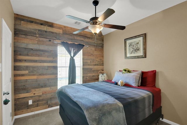 bedroom with carpet, wood walls, and ceiling fan